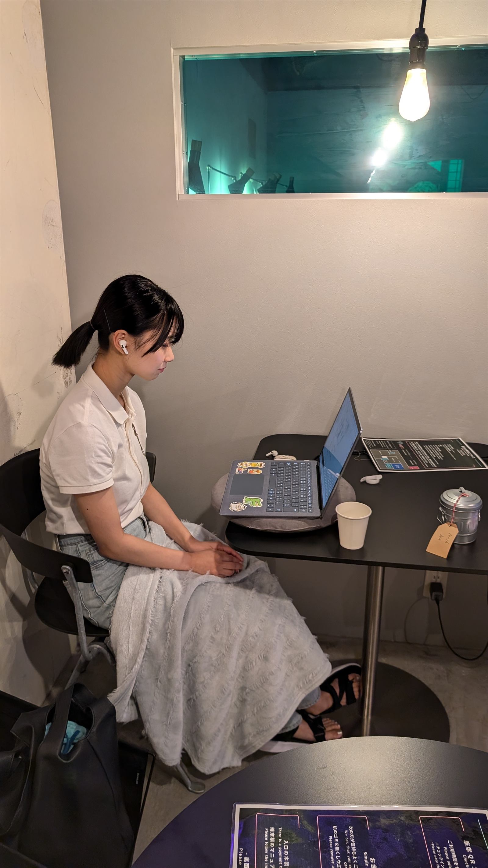 テーブル席でひざ掛けをかけ、ノートPCで作業する利用者